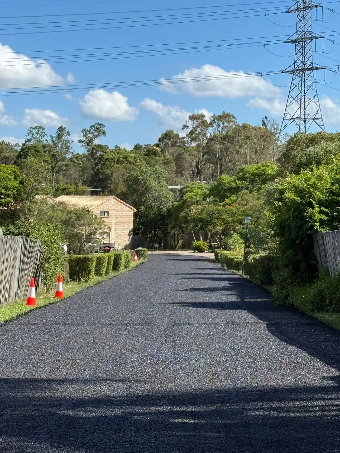Newly laid black bitumen shared driveway leading between residential homes